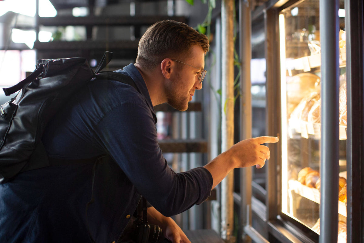 Customer pointing at products in a glass door commercial fridge