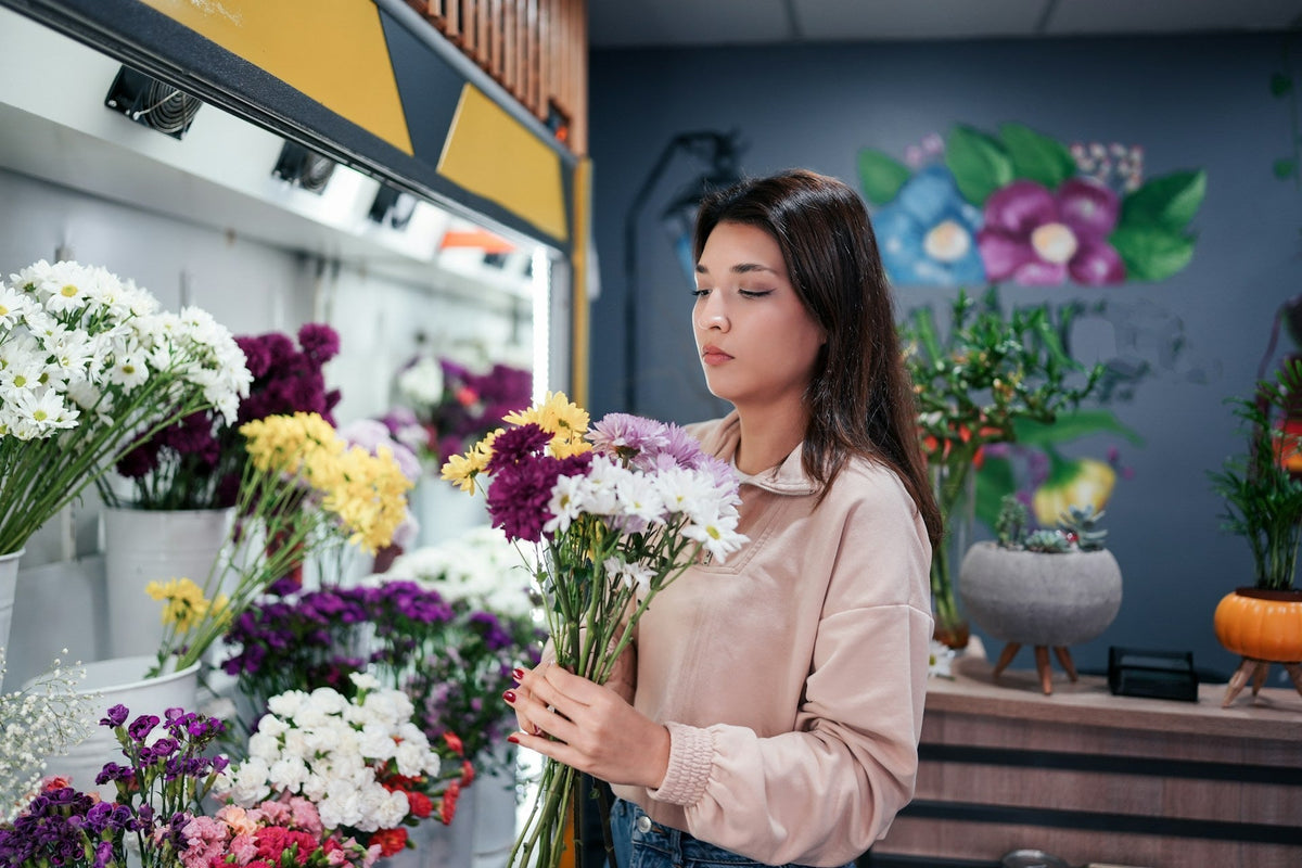Florist holding a fresh bouquet in front of a flower display fridge